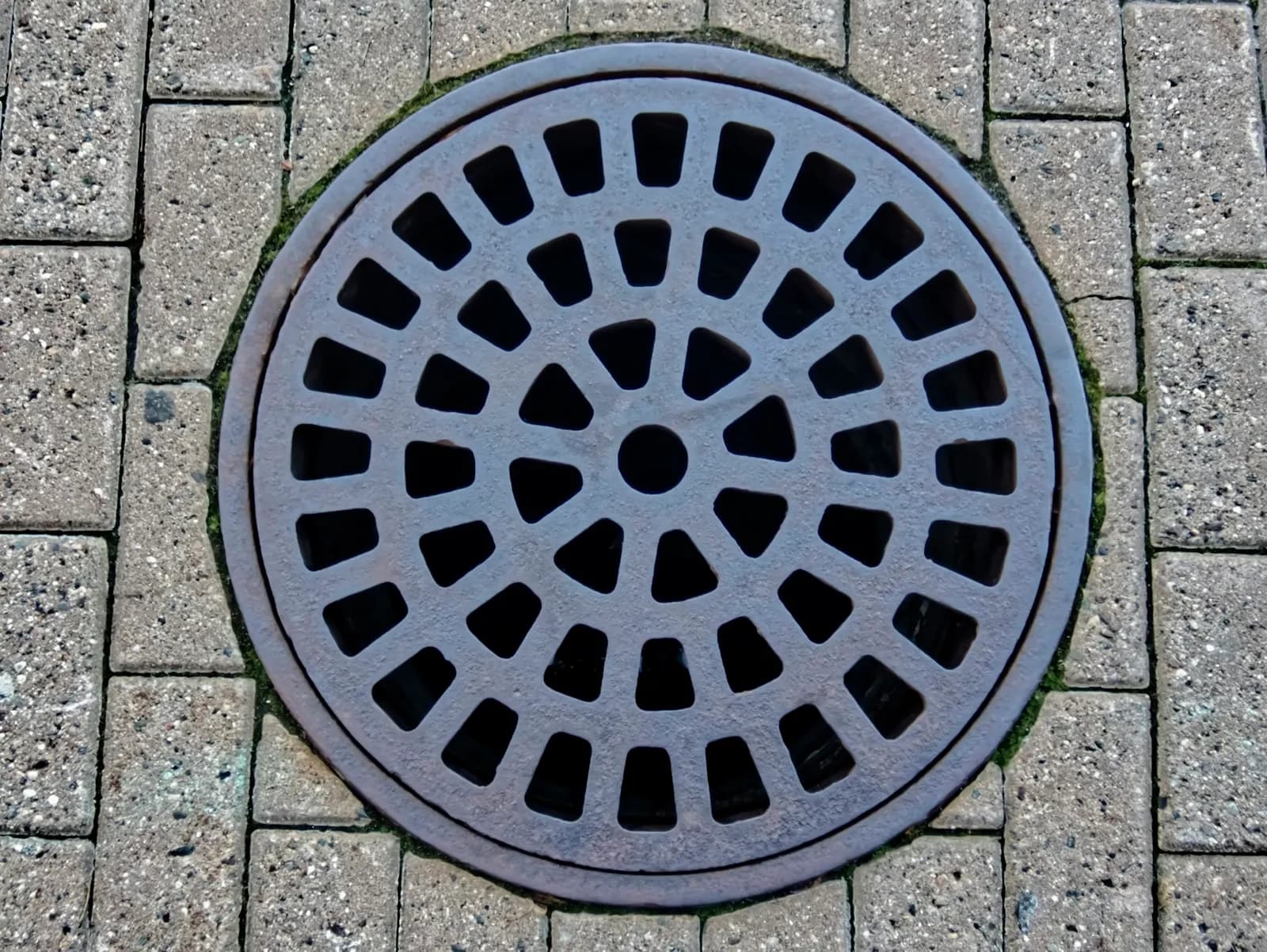Cast iron manhole cover set in block paving